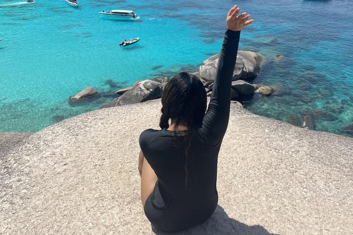 seorang wanita duduk di atas batu melihat air