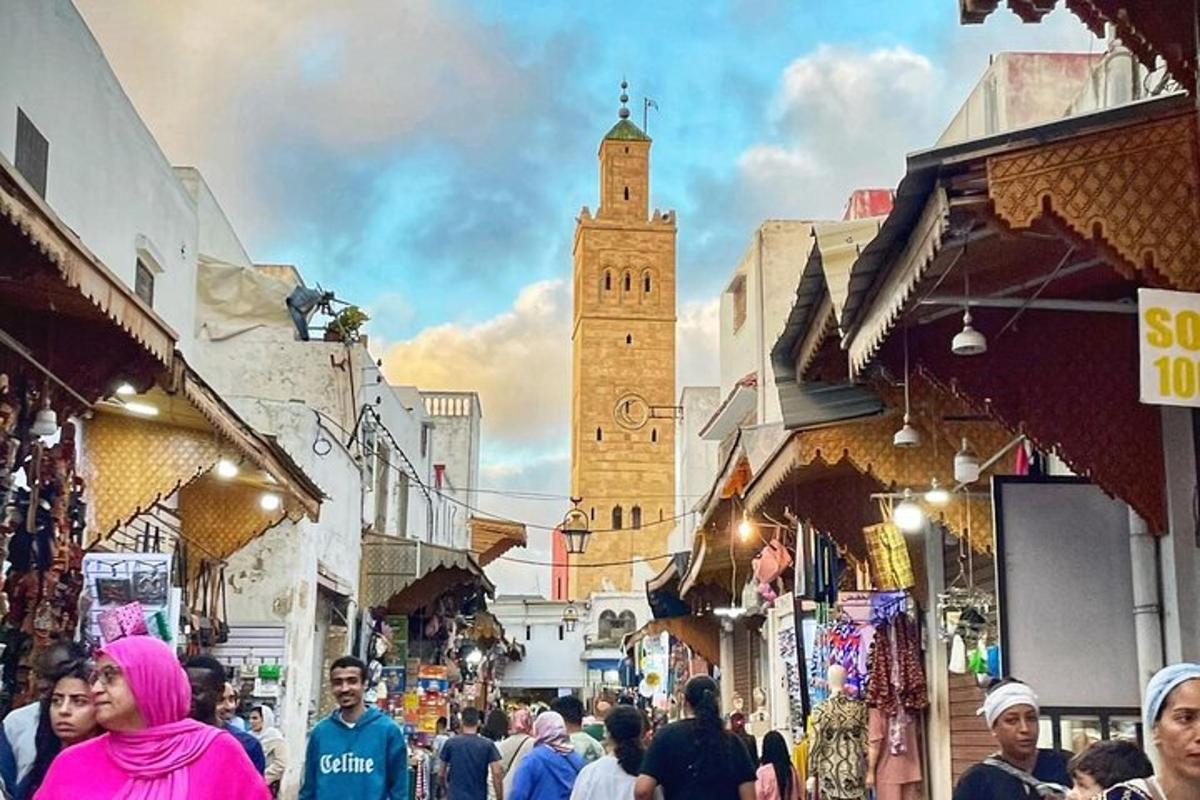 a crowd of people walking through a street with a clock tower