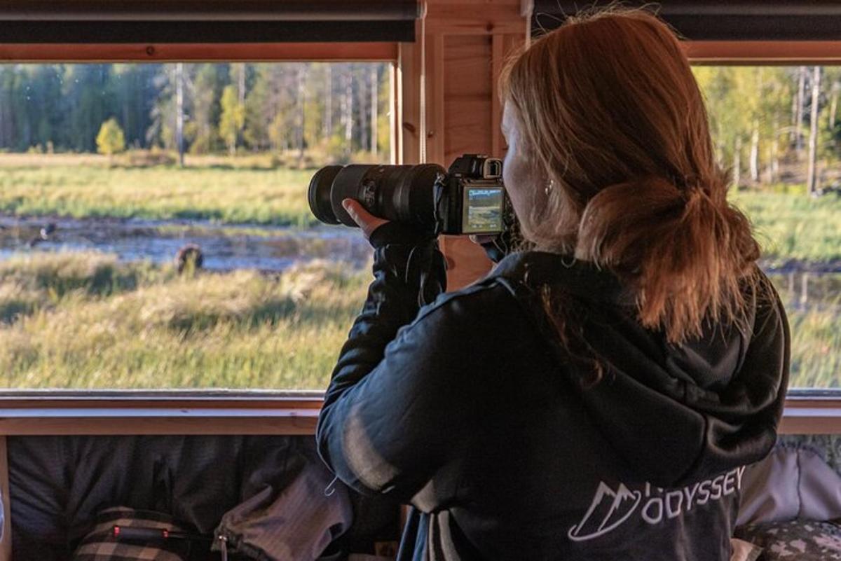 a woman taking a picture of a bear through a window