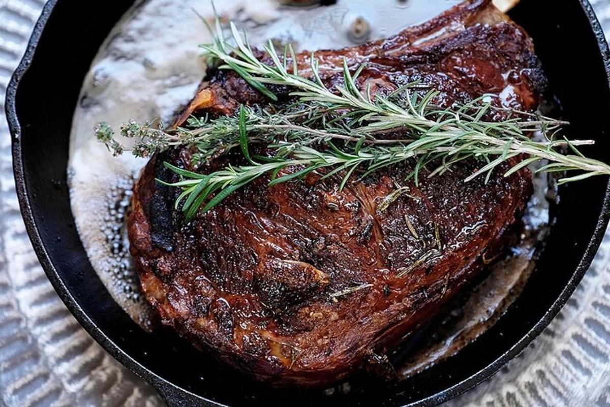 un bistec en una paella de ferro colat amb romaní