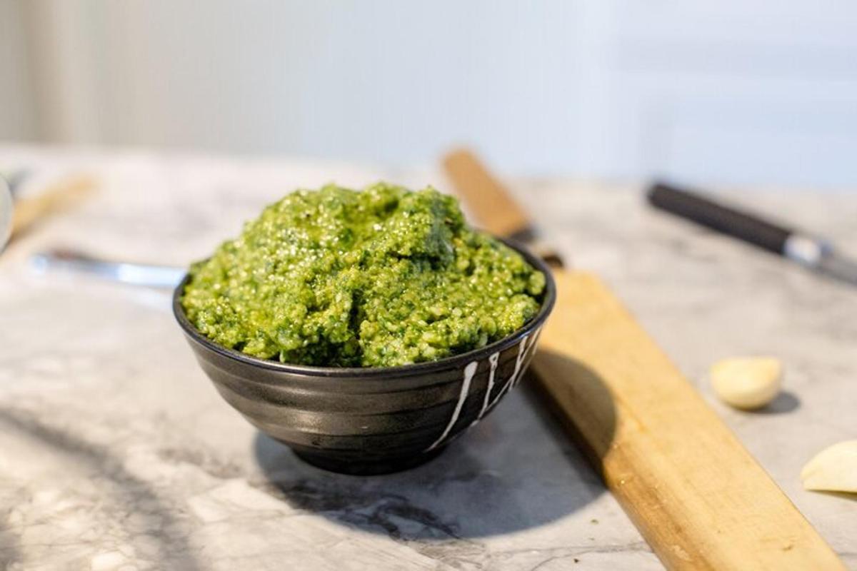 un bol negre ple de pesto verd sobre un taulell