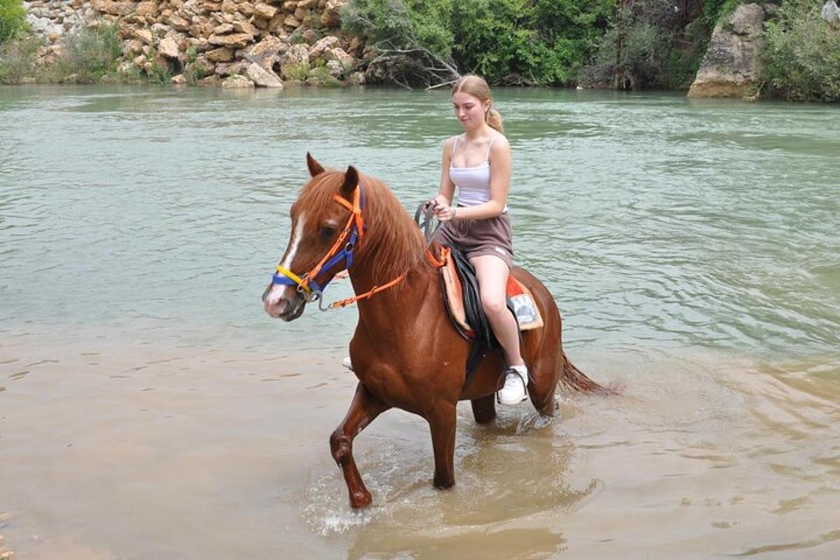 uma mulher cavalgando um cavalo através da água