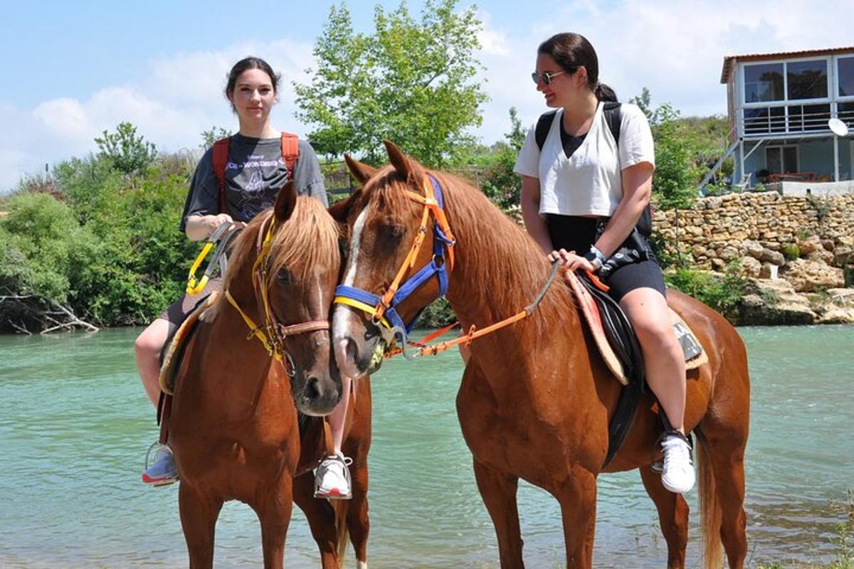 duas mulheres estão cavalgando na água