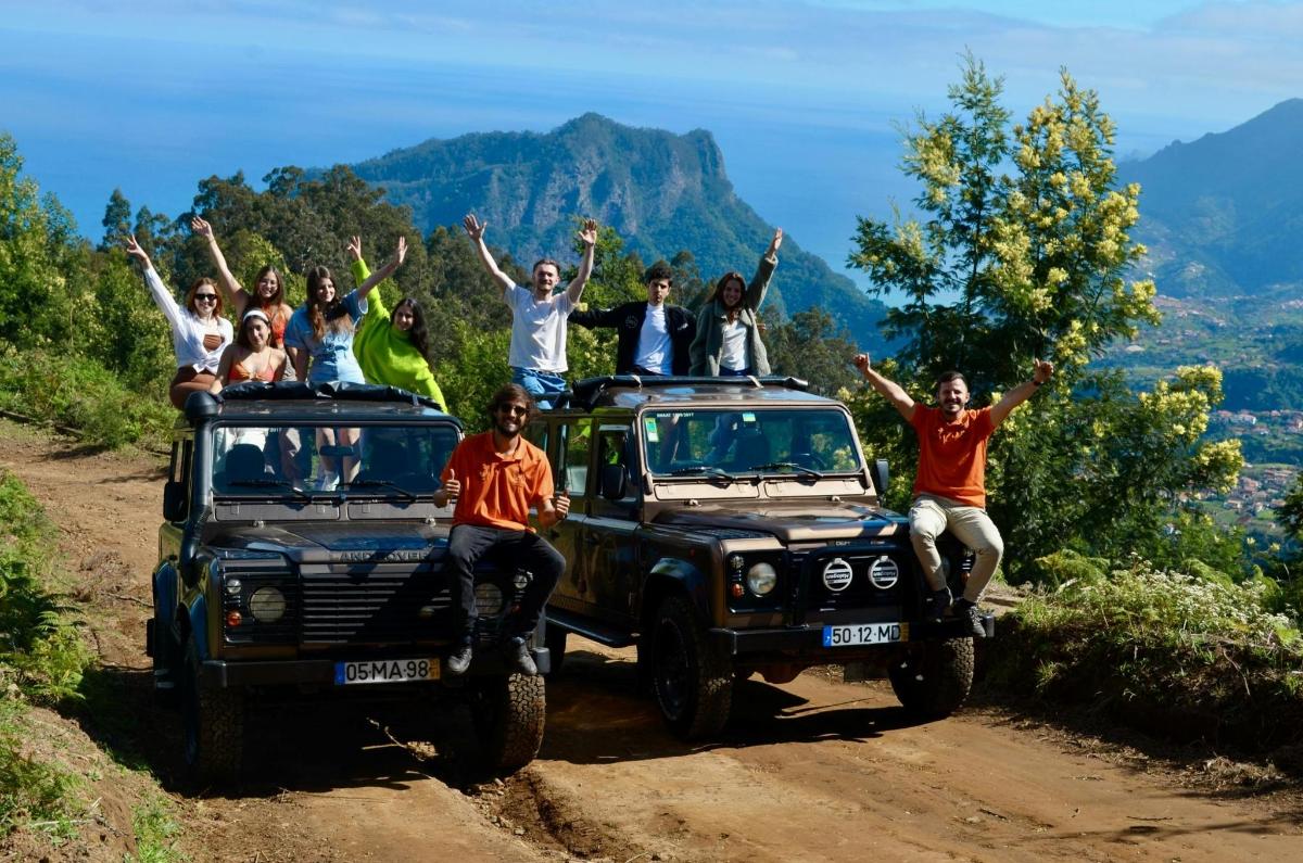 một nhóm người ngồi trên nóc xe jeep của họ trên một con đường đất