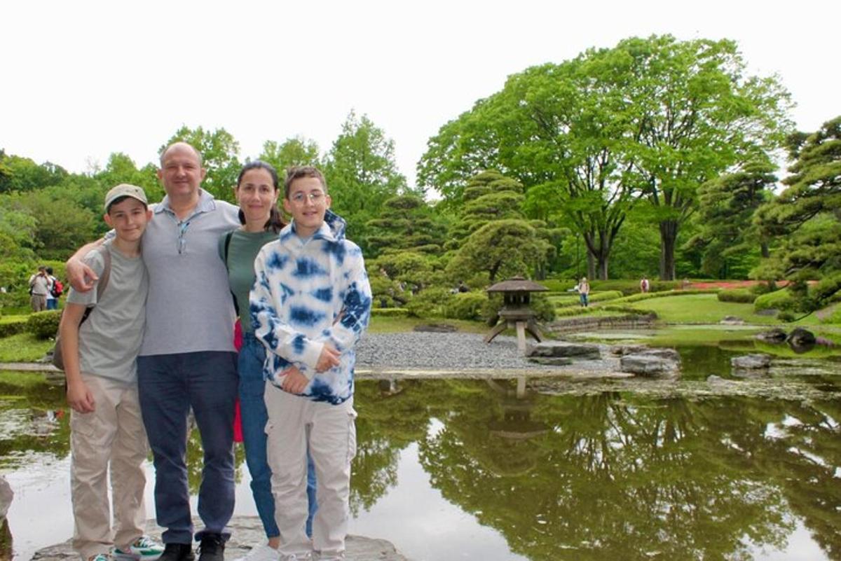 bir aile parktaki bir göletin önünde poz veriyor