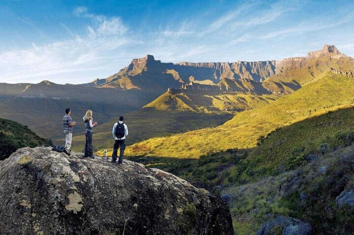 hópur þriggja manna stendur uppi á fjallstindi