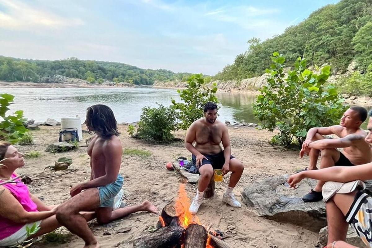 un grup de persones assegudes al voltant d'un foc a la platja