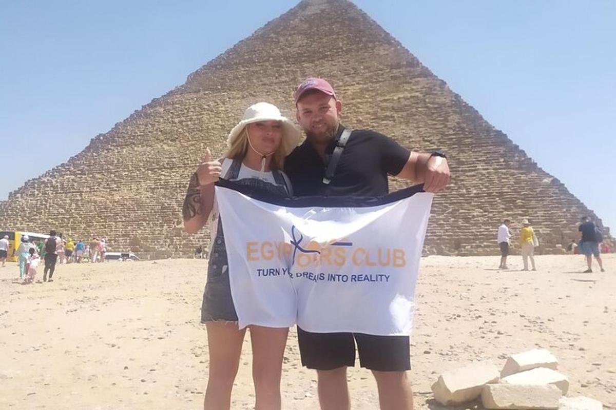 en mand og en kvinde, der holder et skilt foran pyramiderne