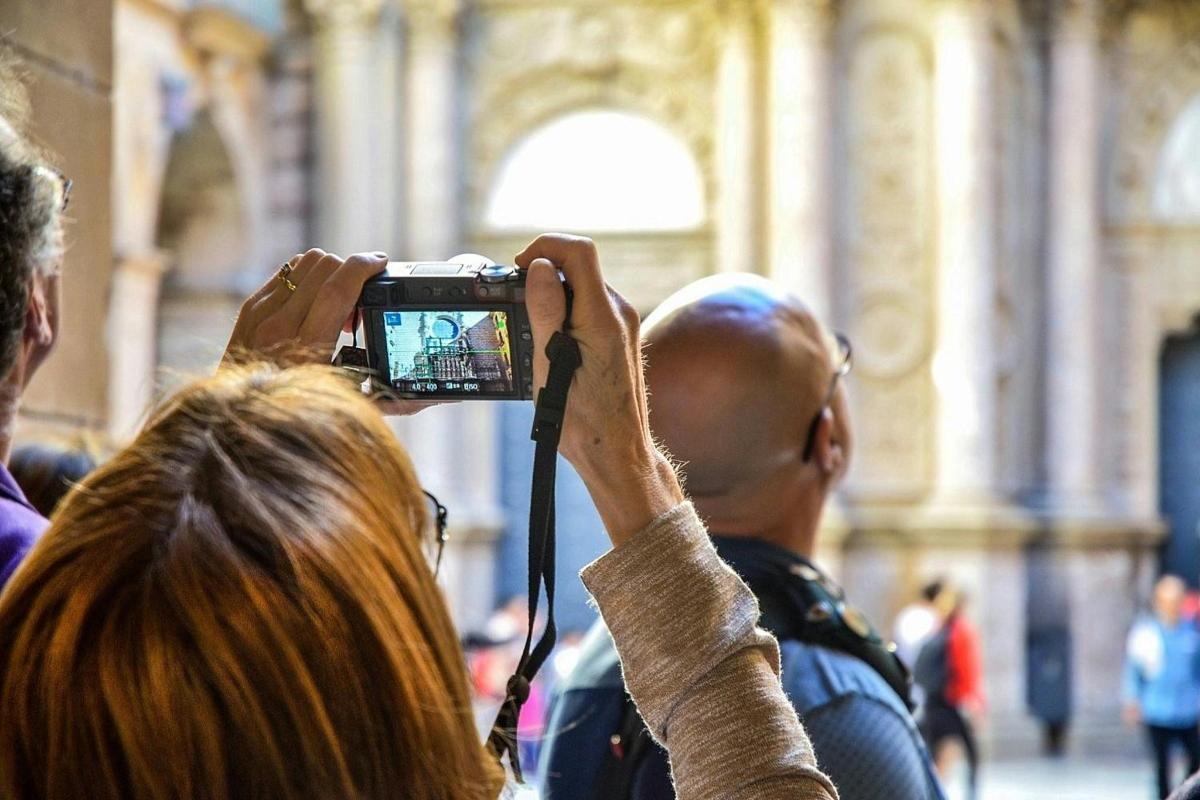 žena fotící osobu fotoaparátem