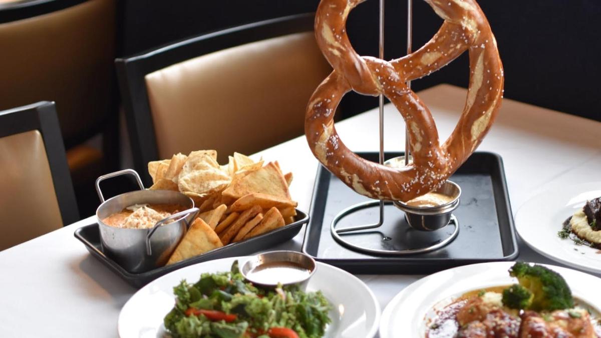 a table with plates of food and a pretzel and chips