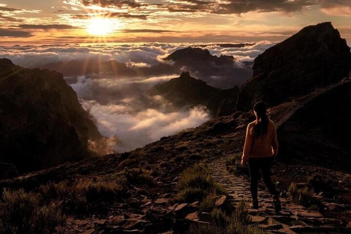 una donna che cammina lungo un sentiero su una montagna al tramonto