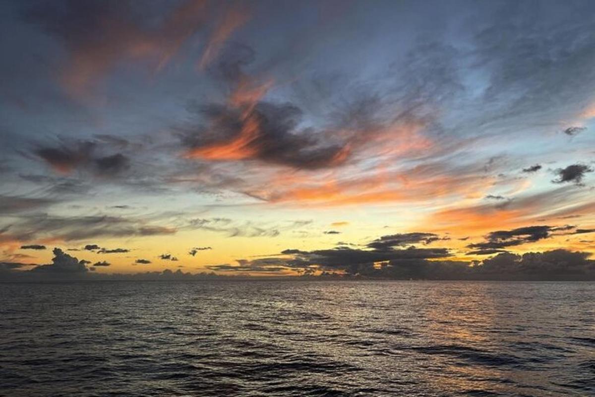 Západ slunce nad oceánem se zataženou oblohou