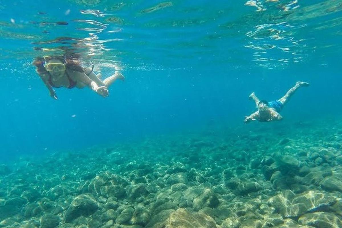 two people swimming in the water near the reef