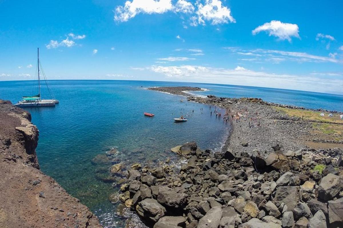 a group of people on a rocky beach with boats in the water