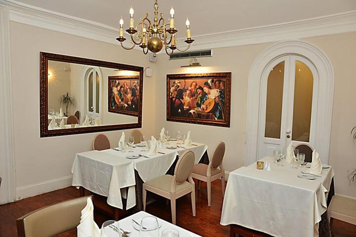 uma sala de jantar com mesas e cadeiras brancas e um lustre