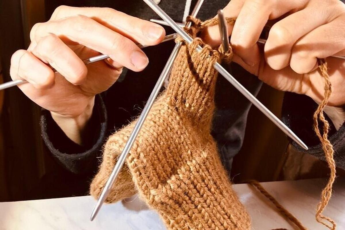 una persona che lavora a maglia un pezzo di filato con i ferri da maglia