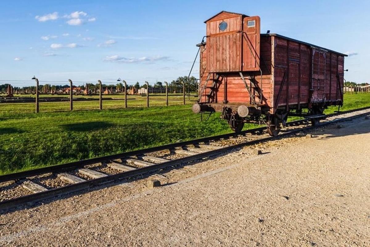 un vagon de tren stând pe șinele de lângă un câmp