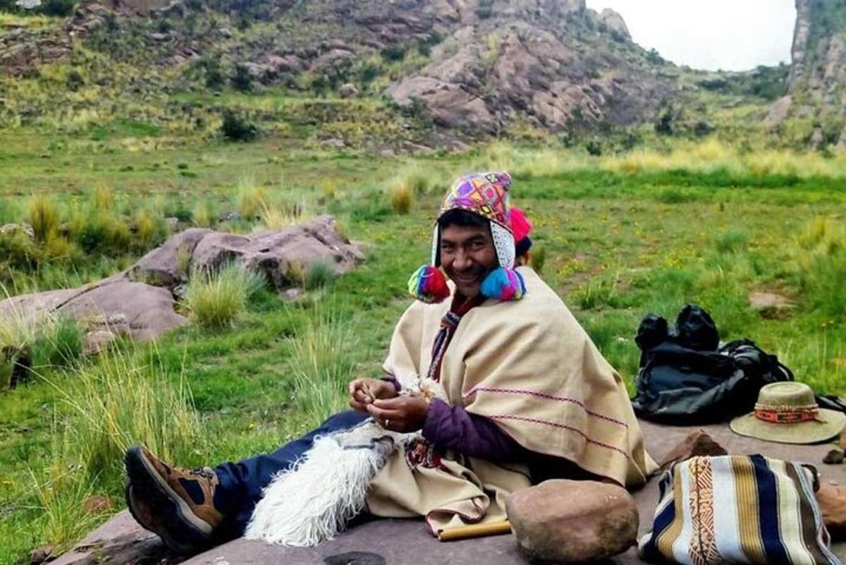 un uomo seduto su una roccia con una capra