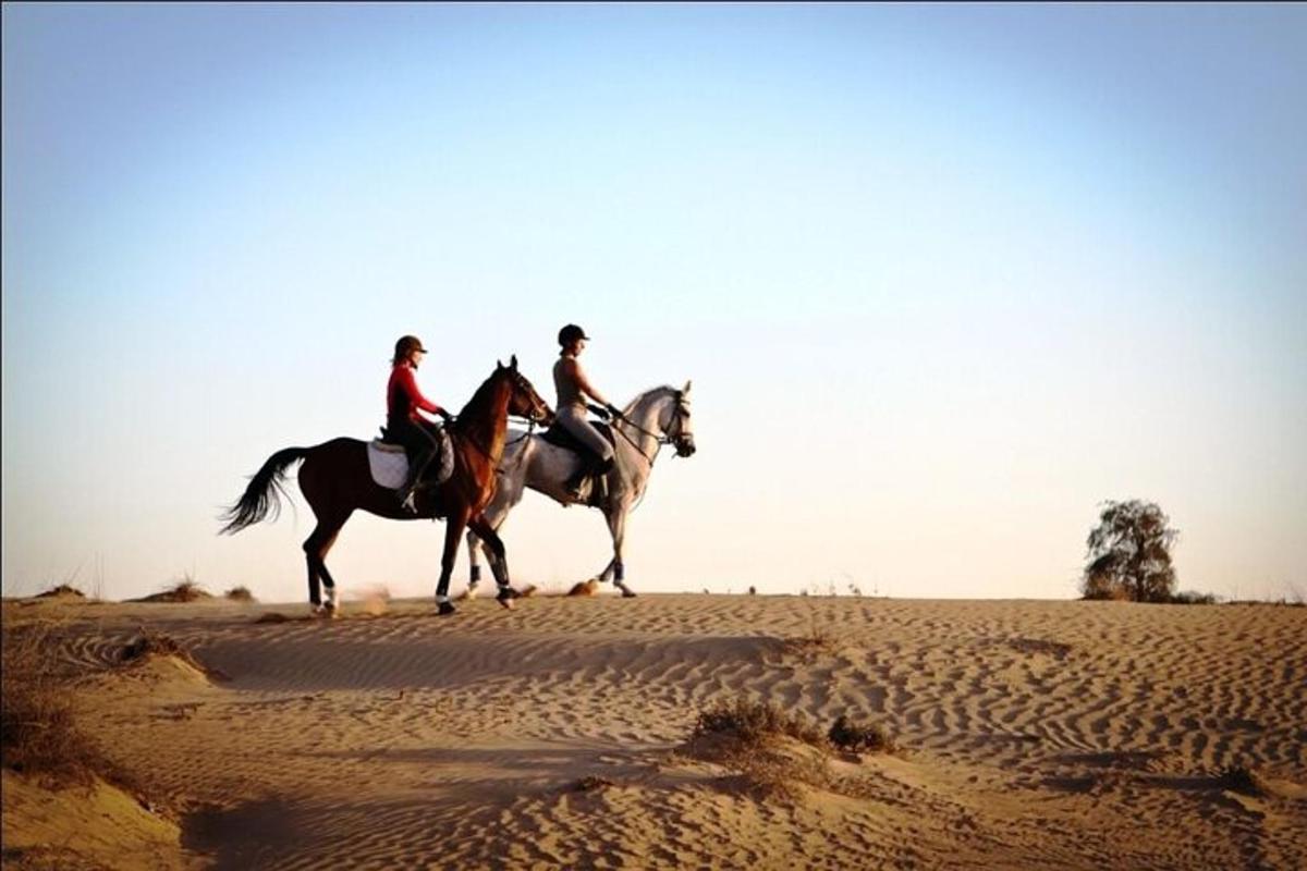 duas pessoas estão cavalgando no deserto