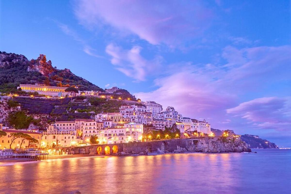 Un pueblo en una colina junto al agua por la noche.
