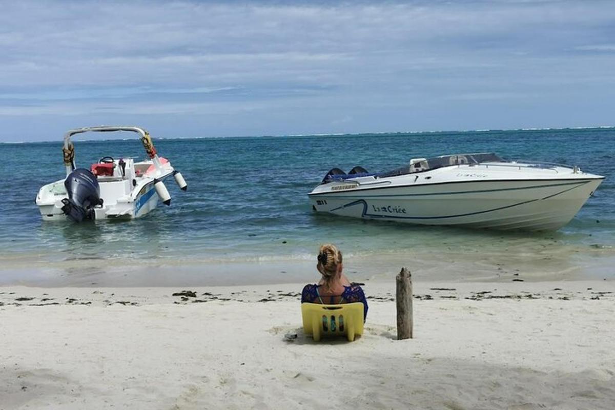 una donna seduta su una sedia su una spiaggia con due barche