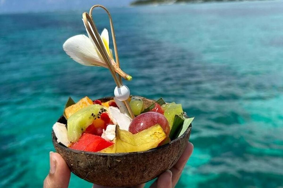 una persona che tiene una ciotola di frutta davanti all'acqua