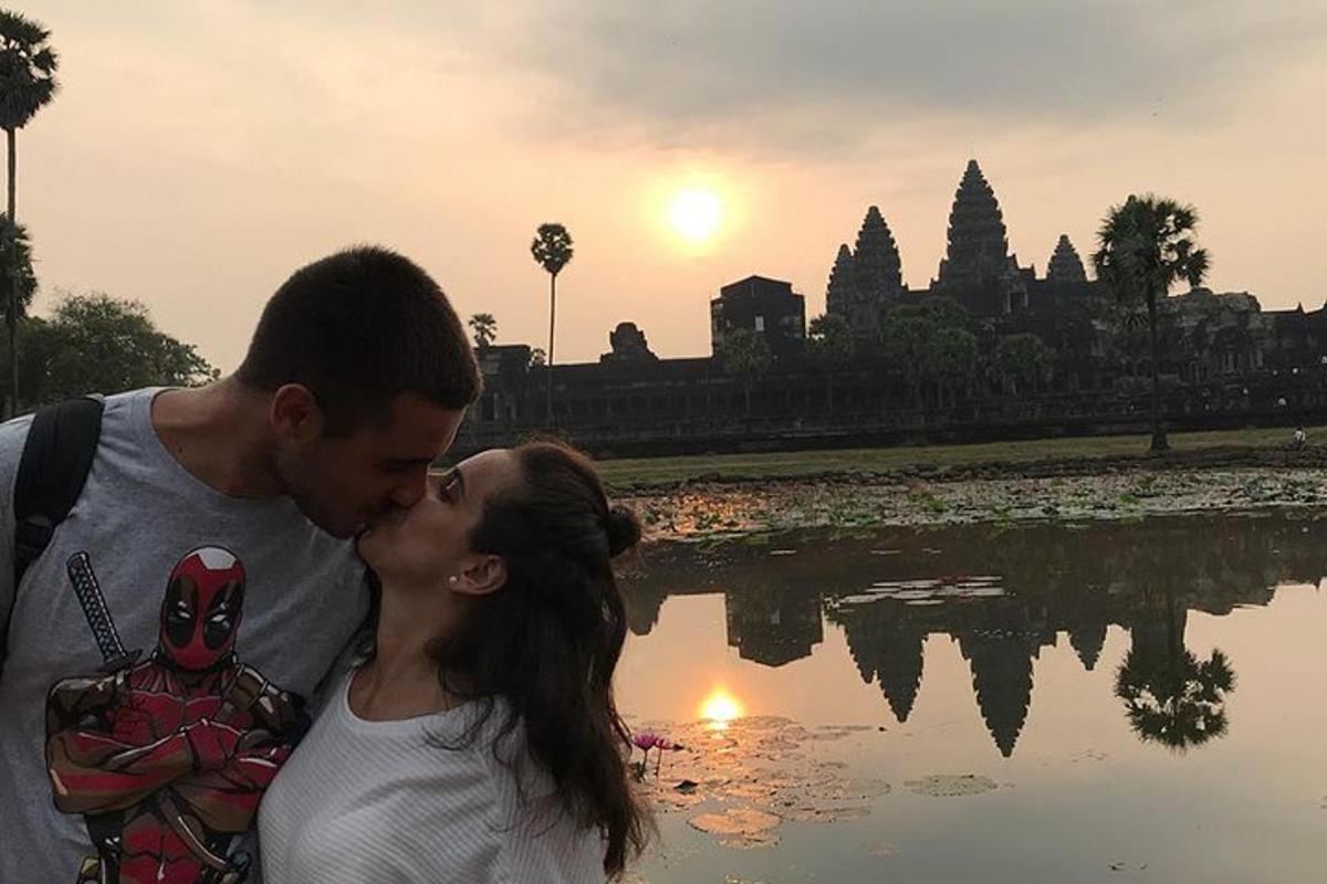 a man and woman kissing in front of a body of water