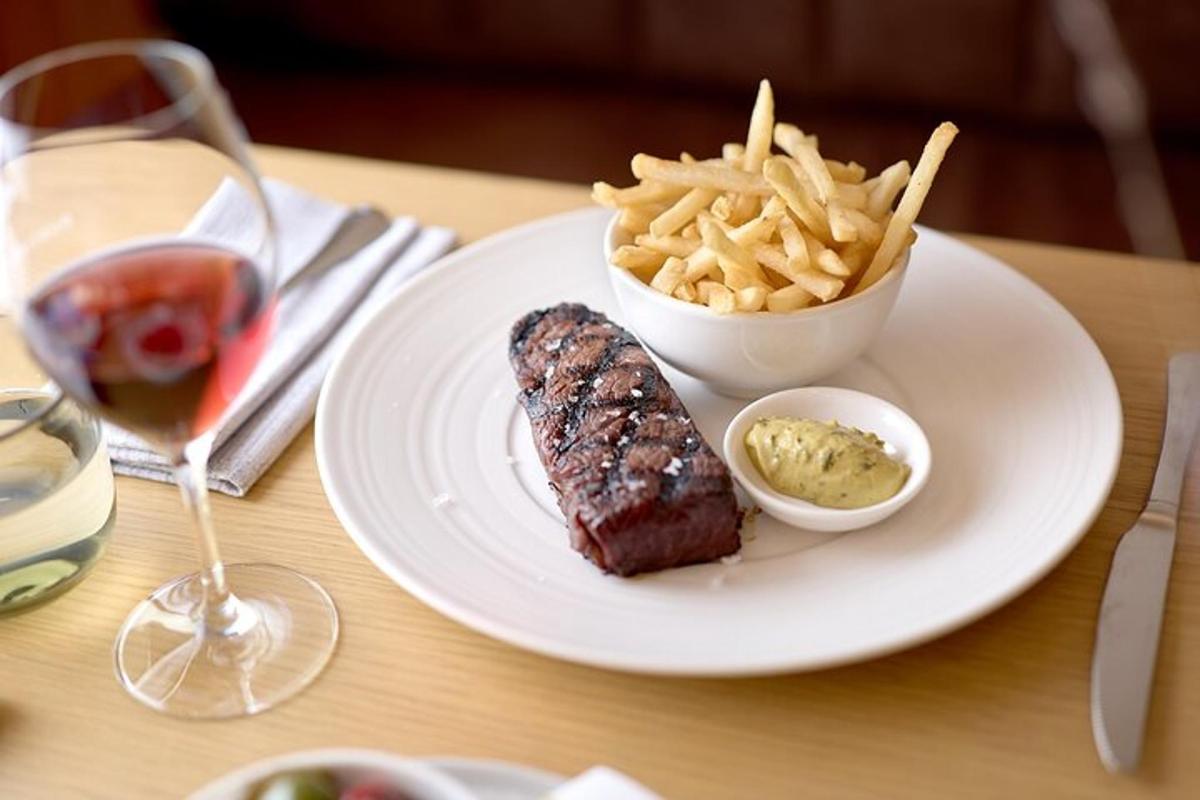 a plate of steak and french fries and a glass of wine