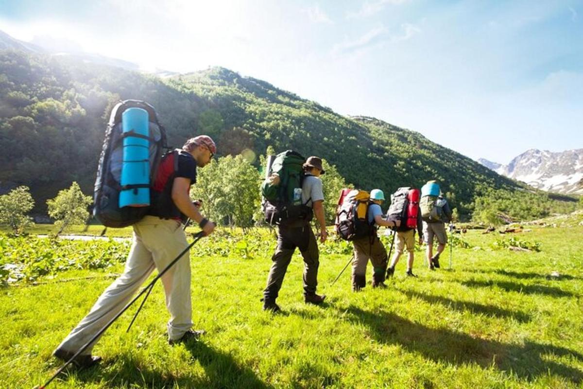 un grup de oameni care urcă un deal cu rucsacuri