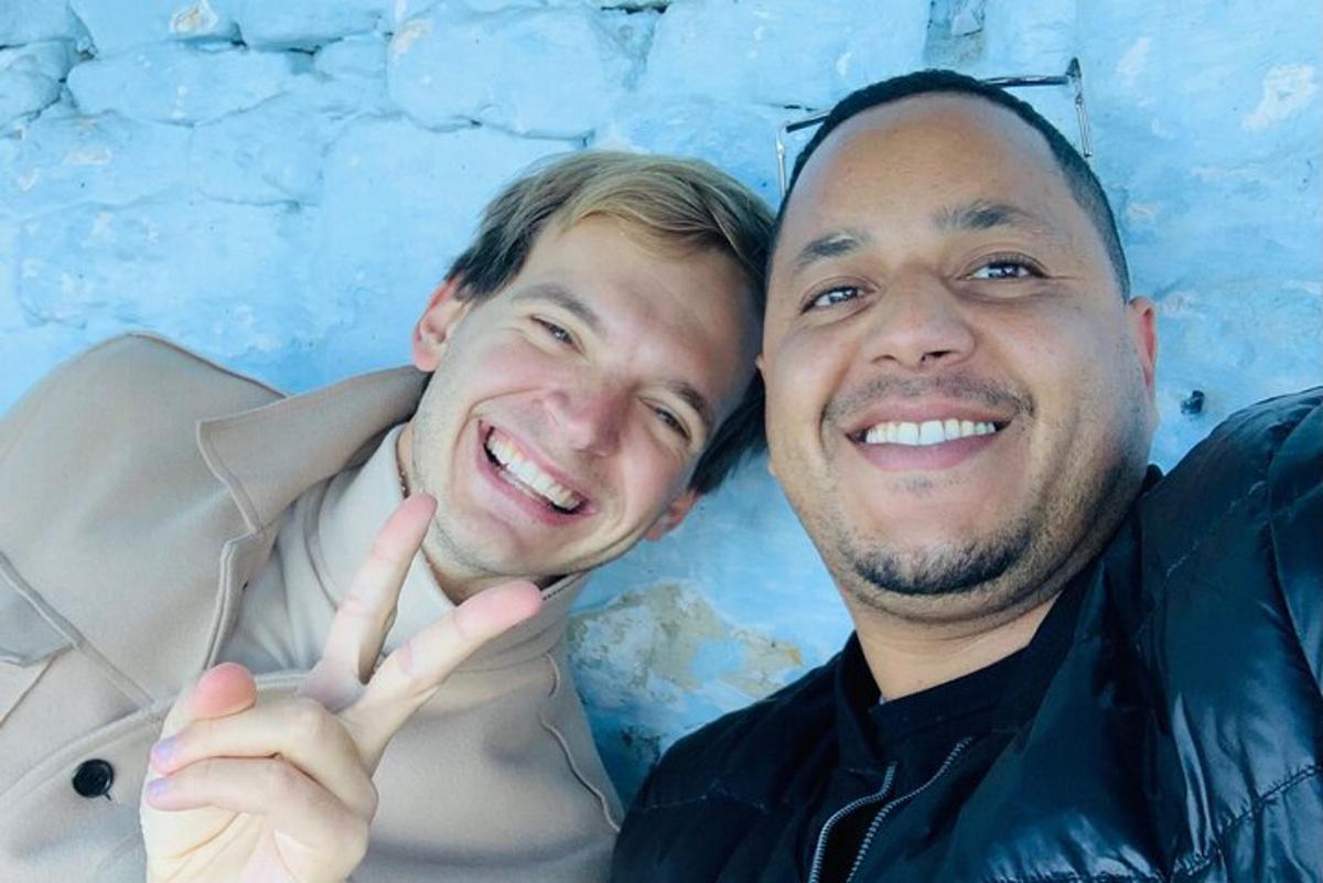 two men posing for a picture in front of a wall