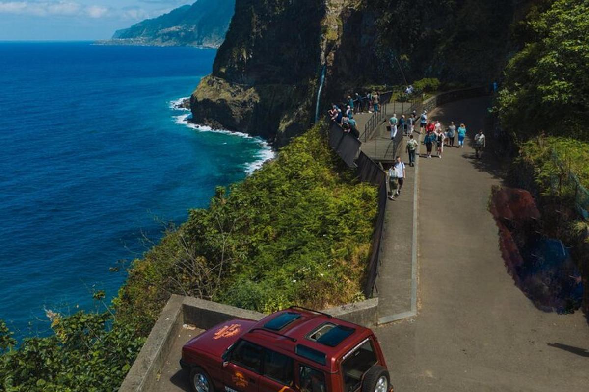 en rød jeep parkert på en klippe ved havet
