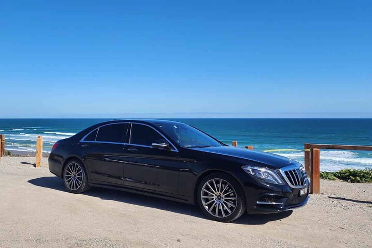 ein schwarzes Auto, das am Strand in der Nähe des Ozeans geparkt ist