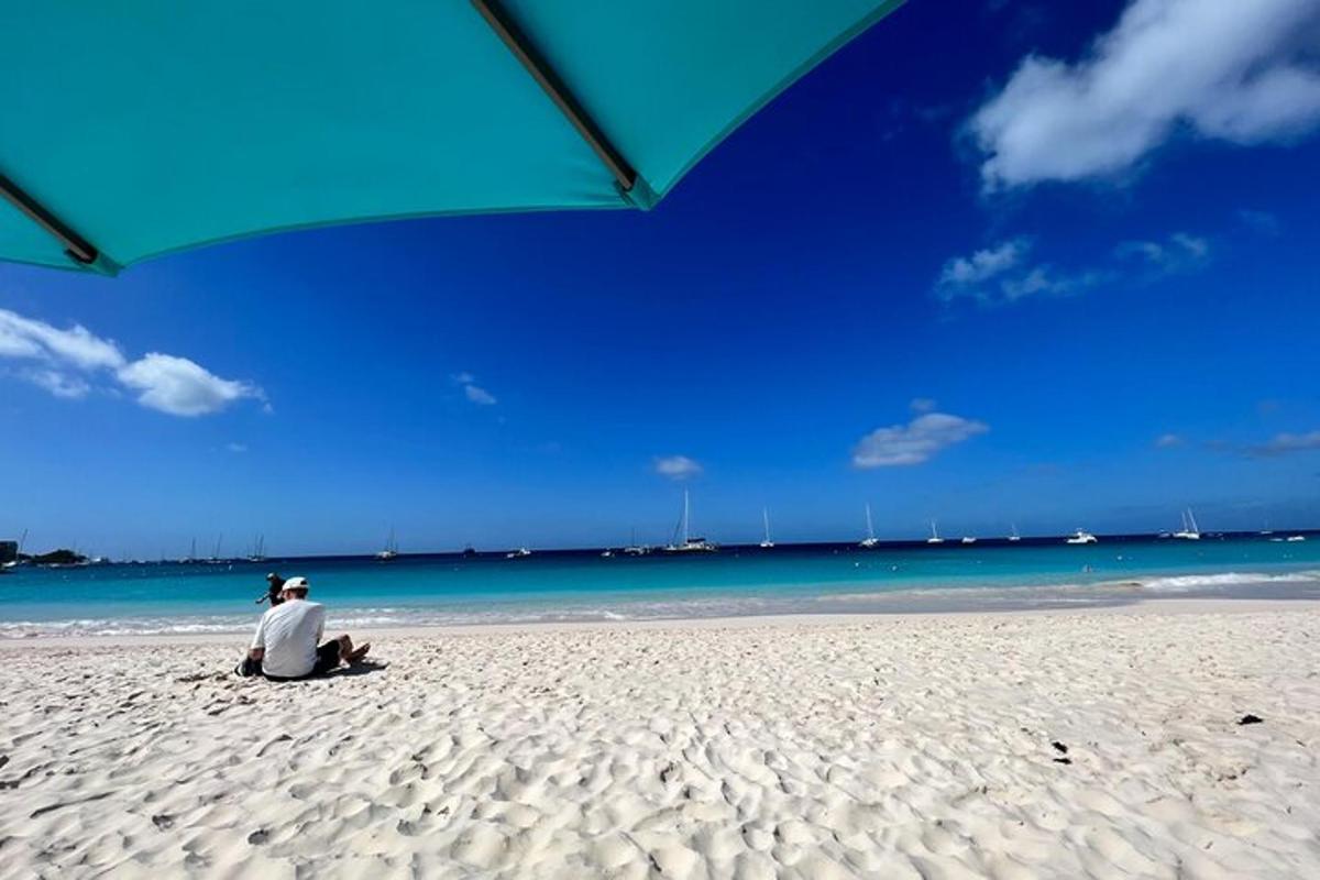 a man sitting on a beach under an umbrella