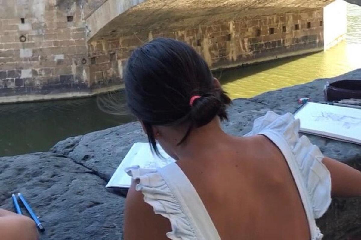 žena sedící na skále a dívající se na vodu