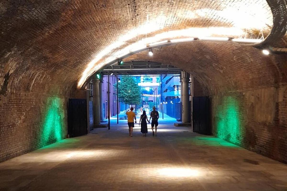 Un grupo de personas caminando por un túnel con luces verdes.