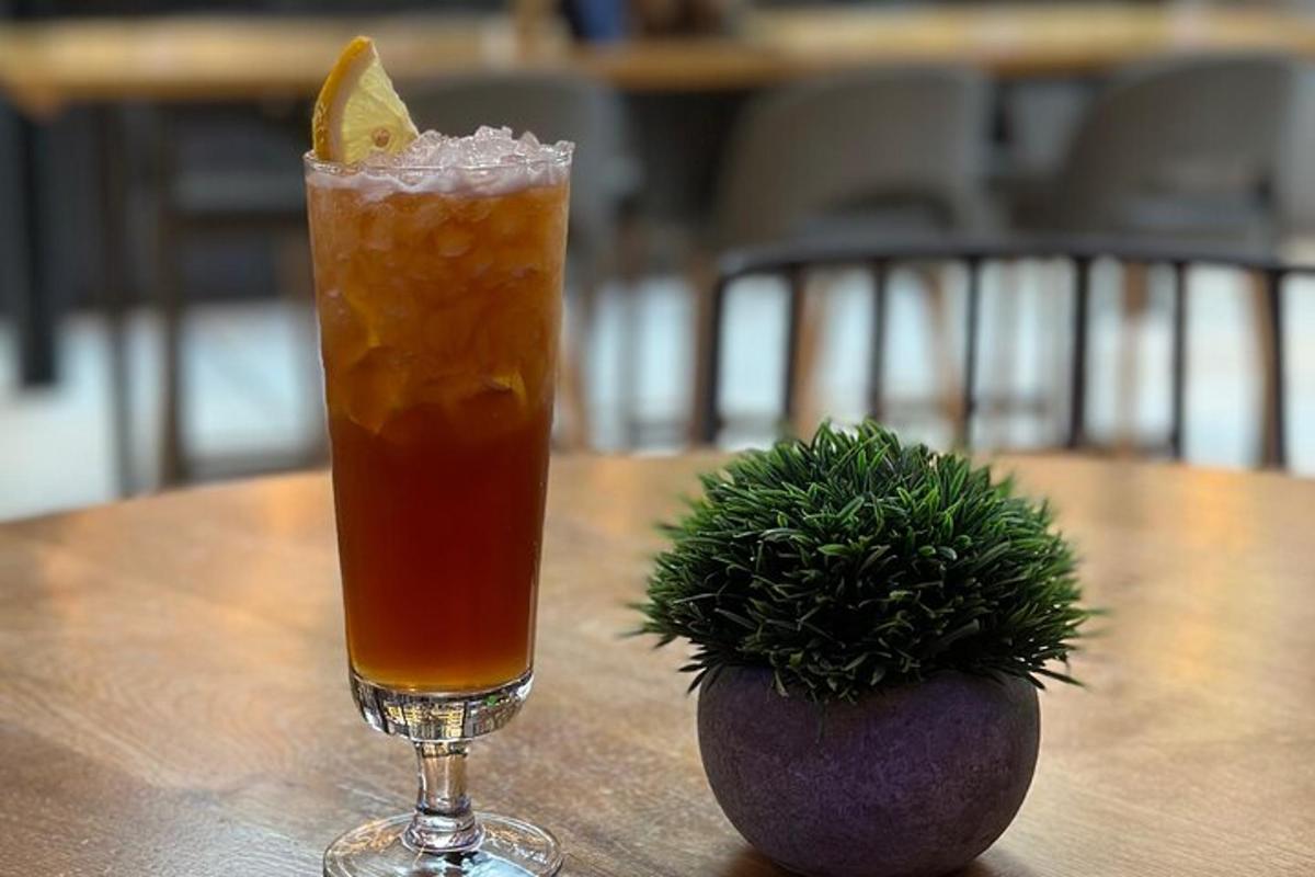 Una bebida en un vaso junto a una planta en una mesa.