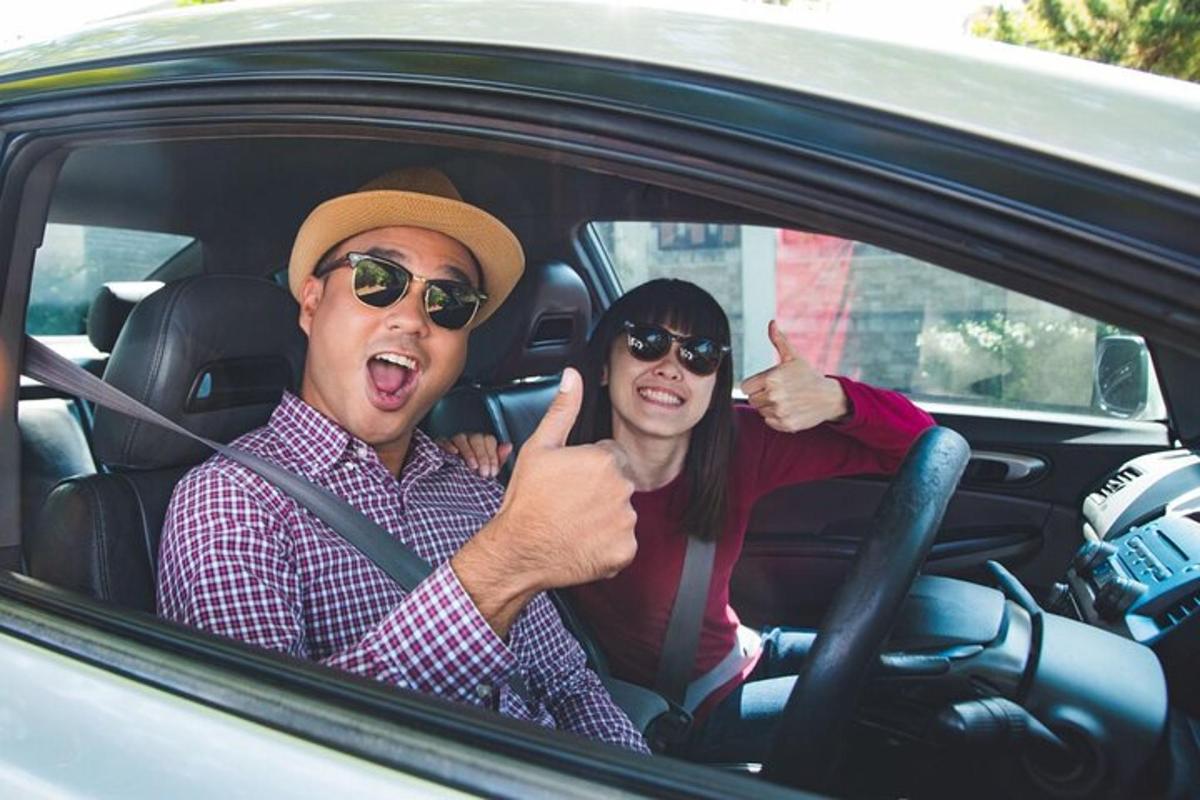 một người đàn ông và một người phụ nữ ngồi trong xe đang giơ ngón tay cái lên