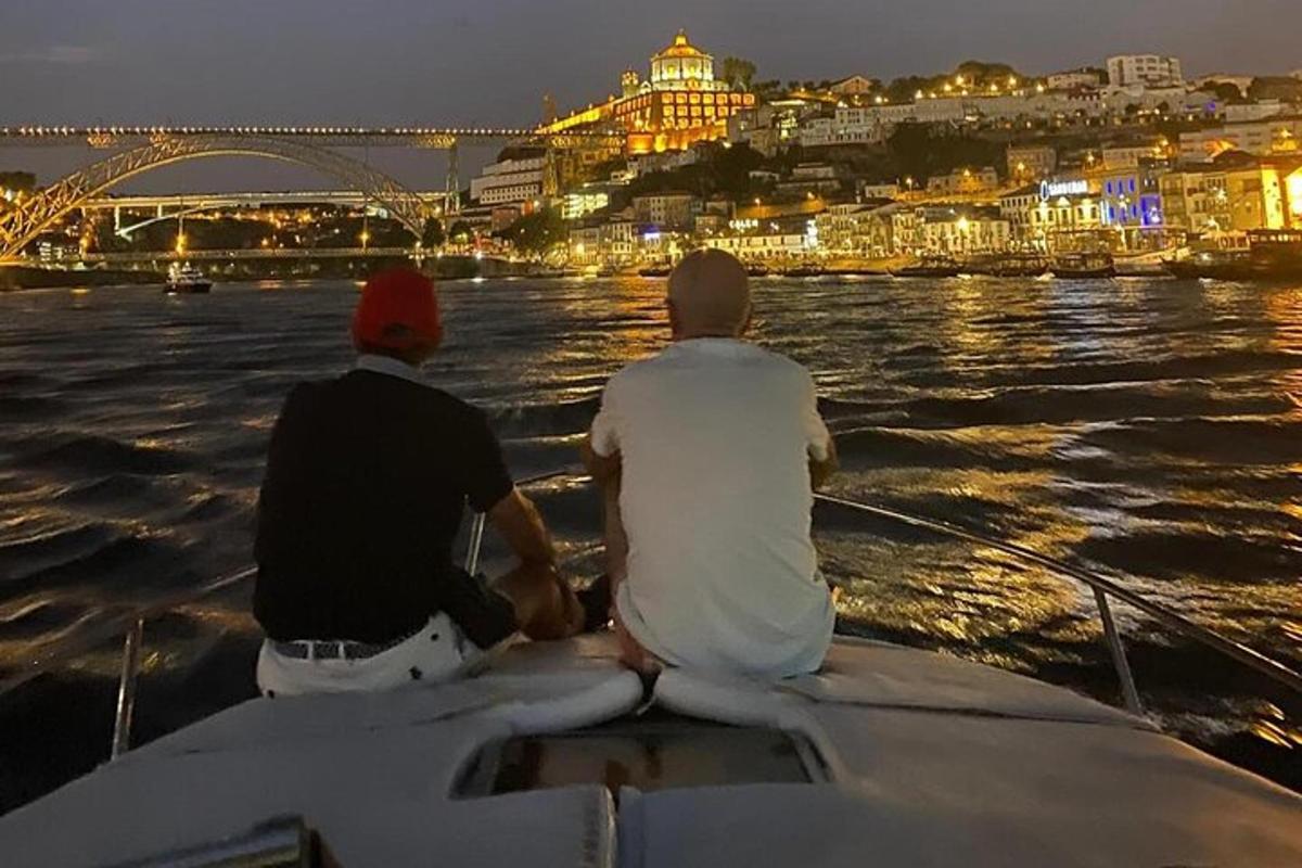 dois homens sentados em um barco na água à noite