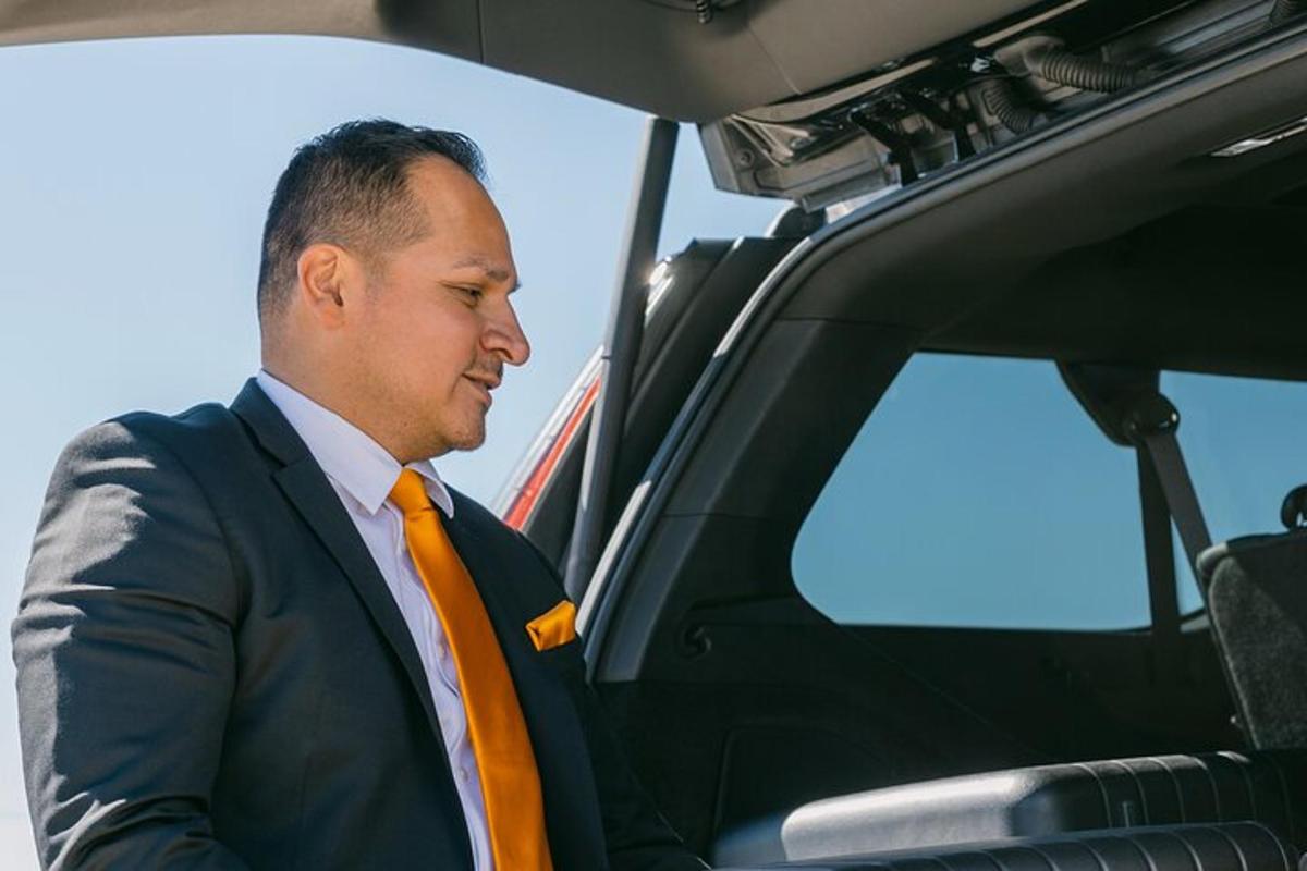 muž v obleku a oranžové kravatě sedící v autě