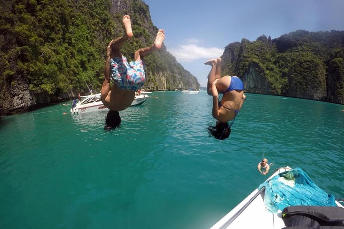 two people jumping off of a boat in the water