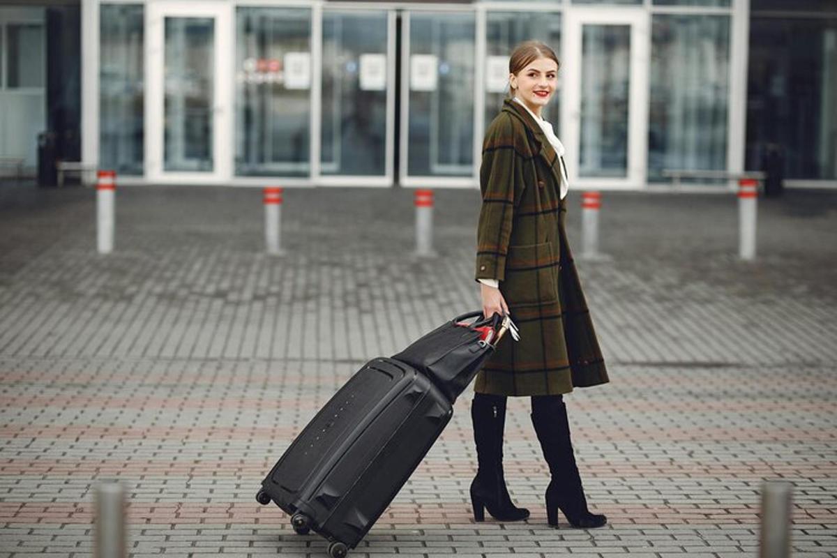 a woman in a coat holding a black suitcase