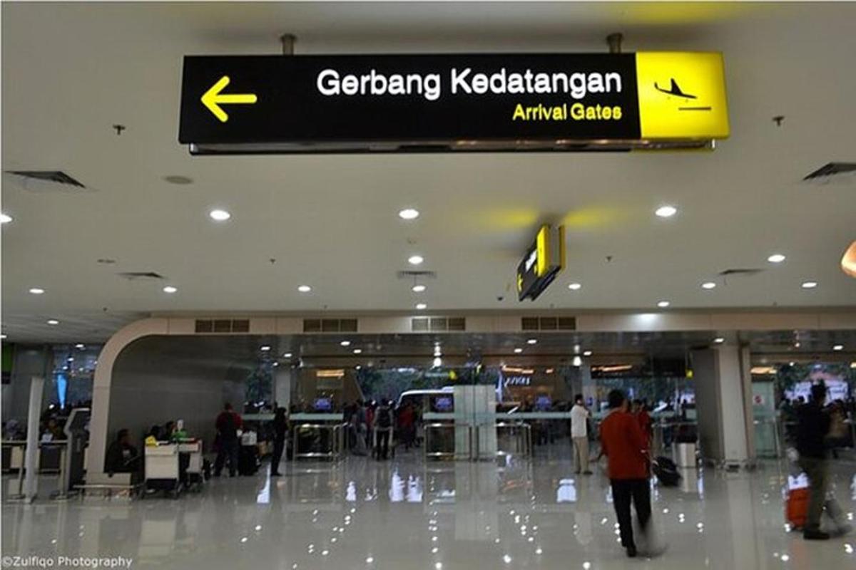 a sign in an airport with people walking around