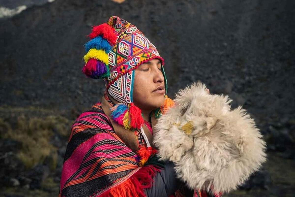 una donna che indossa un copricapo colorato e tiene in mano un animale di peluche