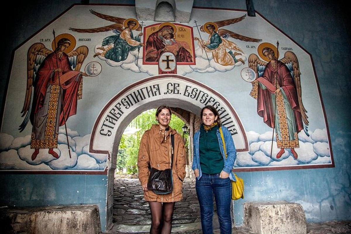 two people standing in front of a church with a mural