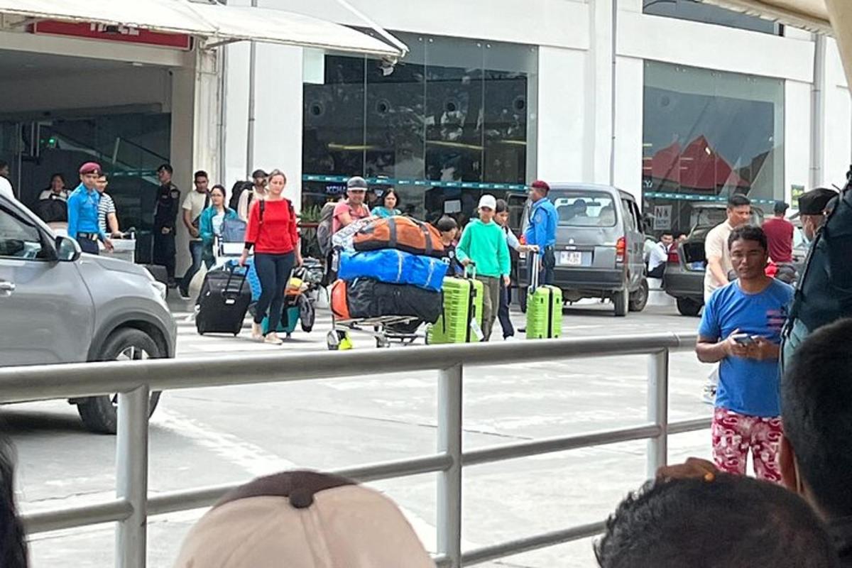 skupina lidí stojících na parkovišti se zavazadly