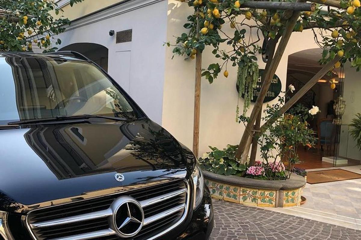 木のある建物の隣に駐車された黒い車