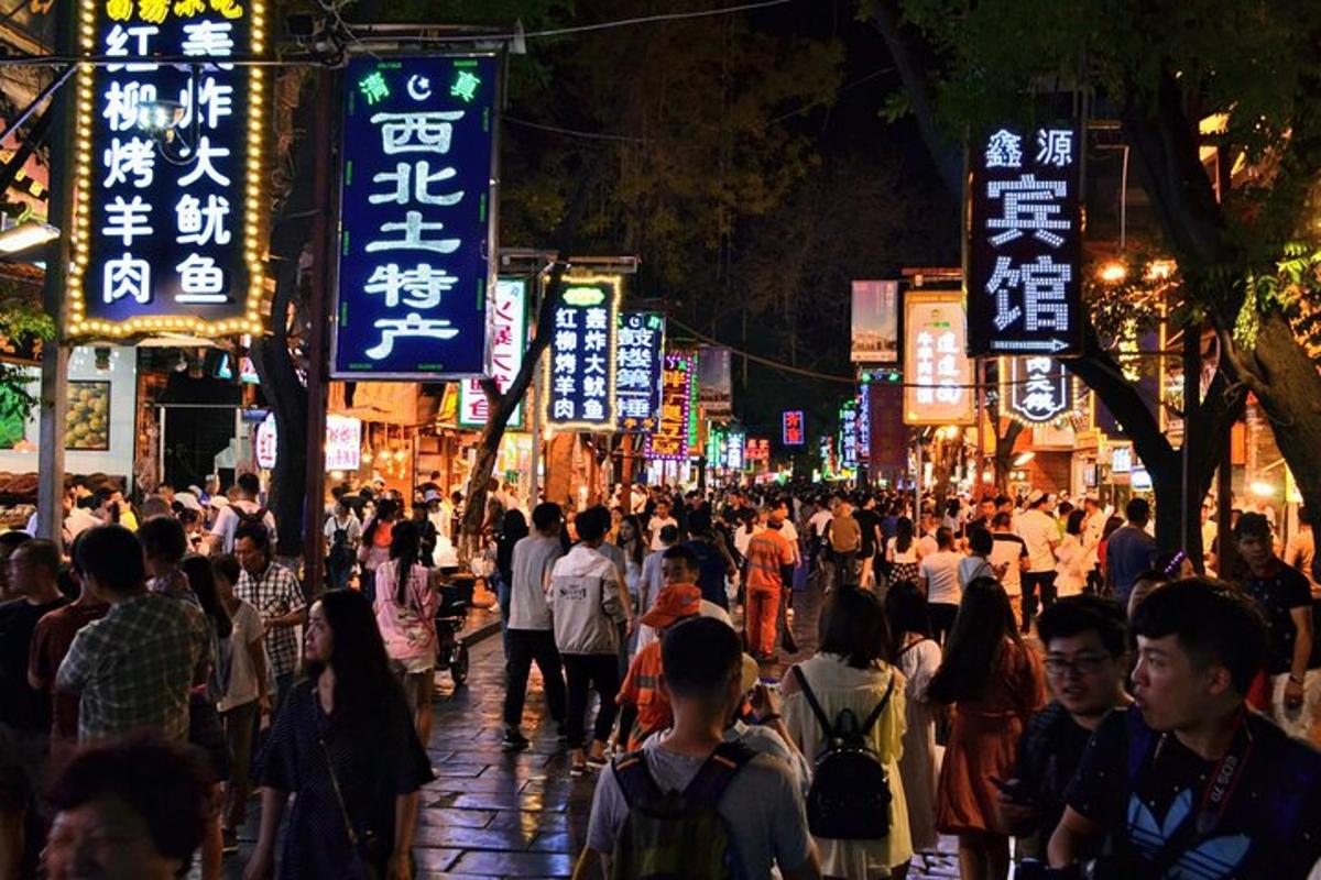 una folla di persone che cammina lungo una strada trafficata di notte
