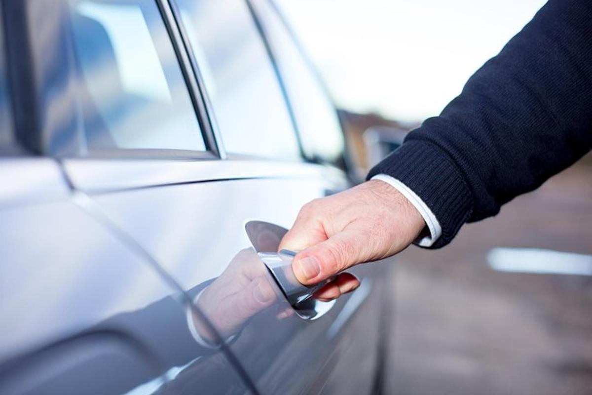 a hand unlocking a car door with a key