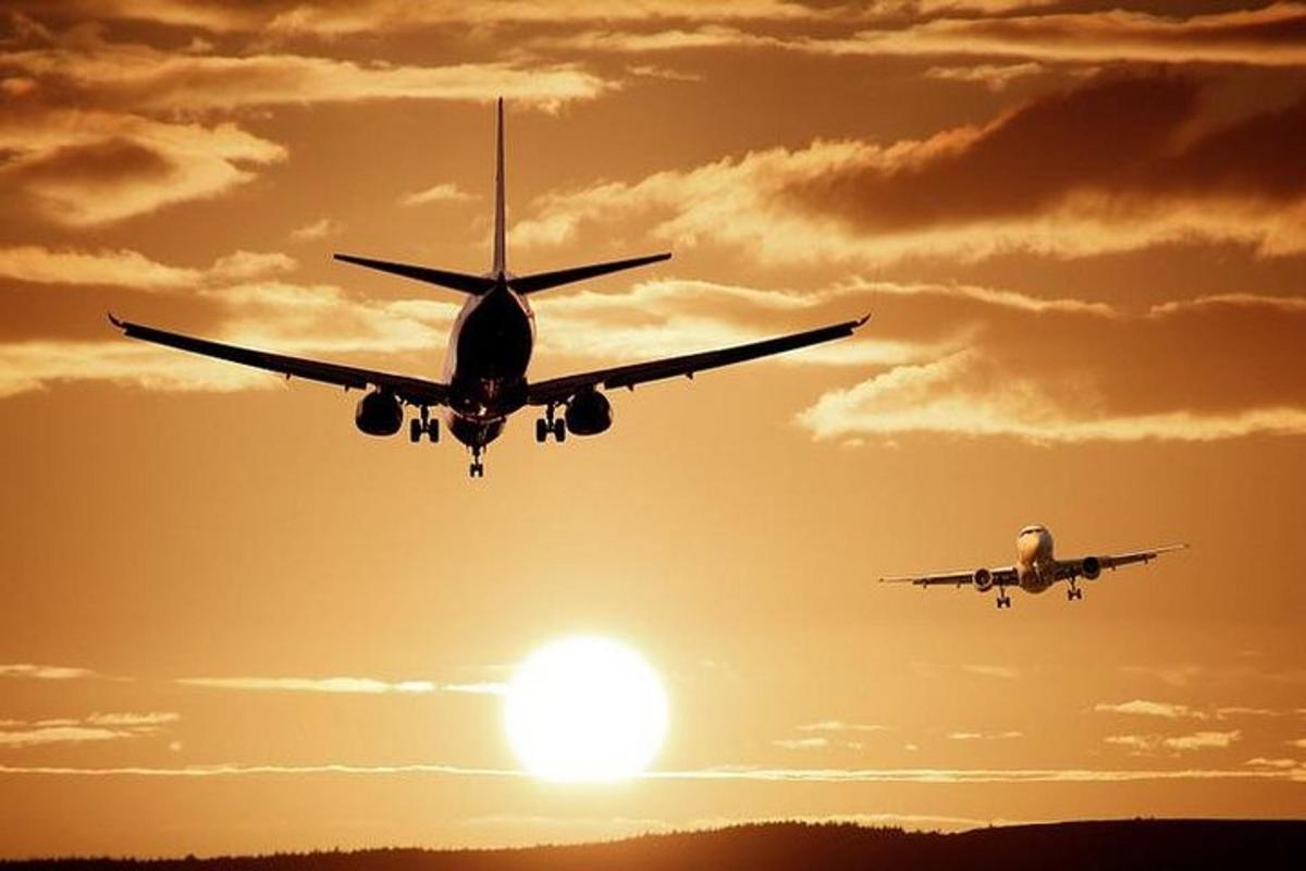 two airplanes flying in the sky at sunset