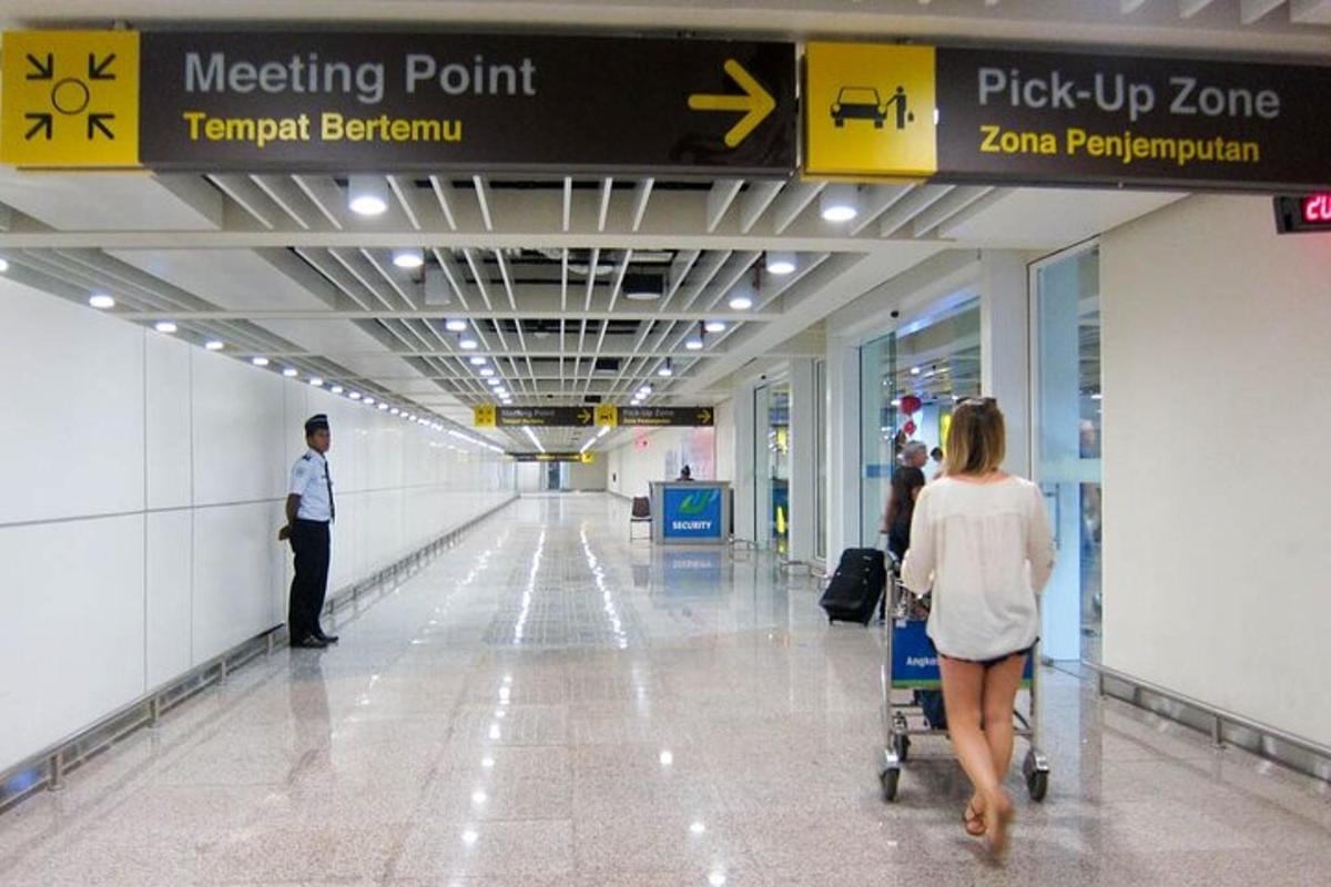 Una mujer empujando un carrito de equipaje en un aeropuerto.